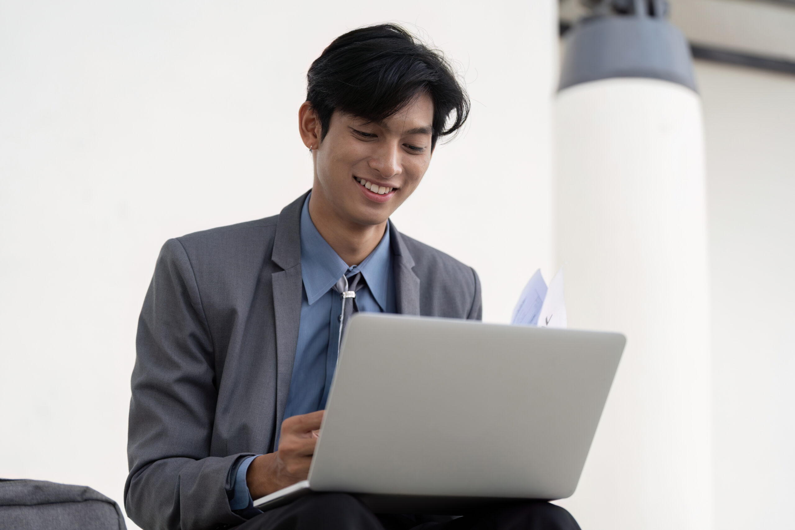 An aspiring business professional reviewing documents while working on a laptop.