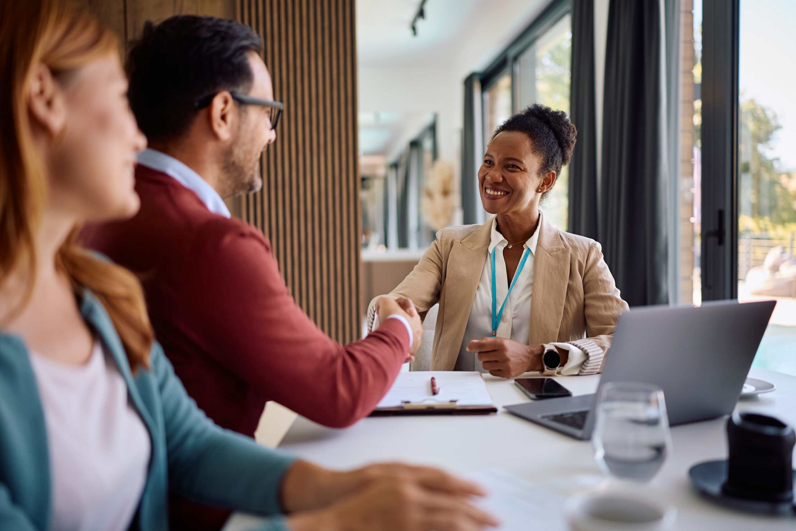 Two business professionals shaking hands in a modern office setting